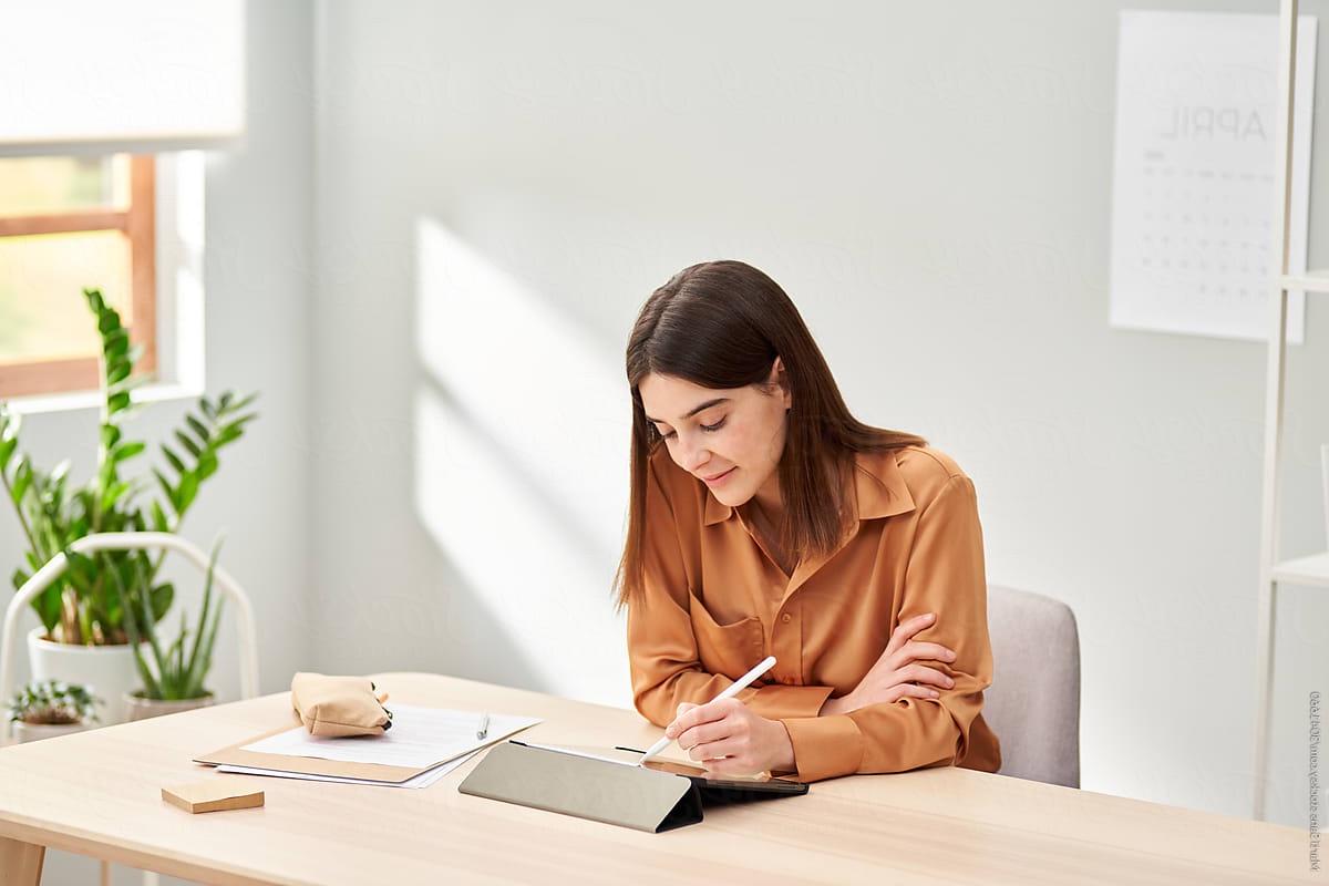 woman writing on tablet